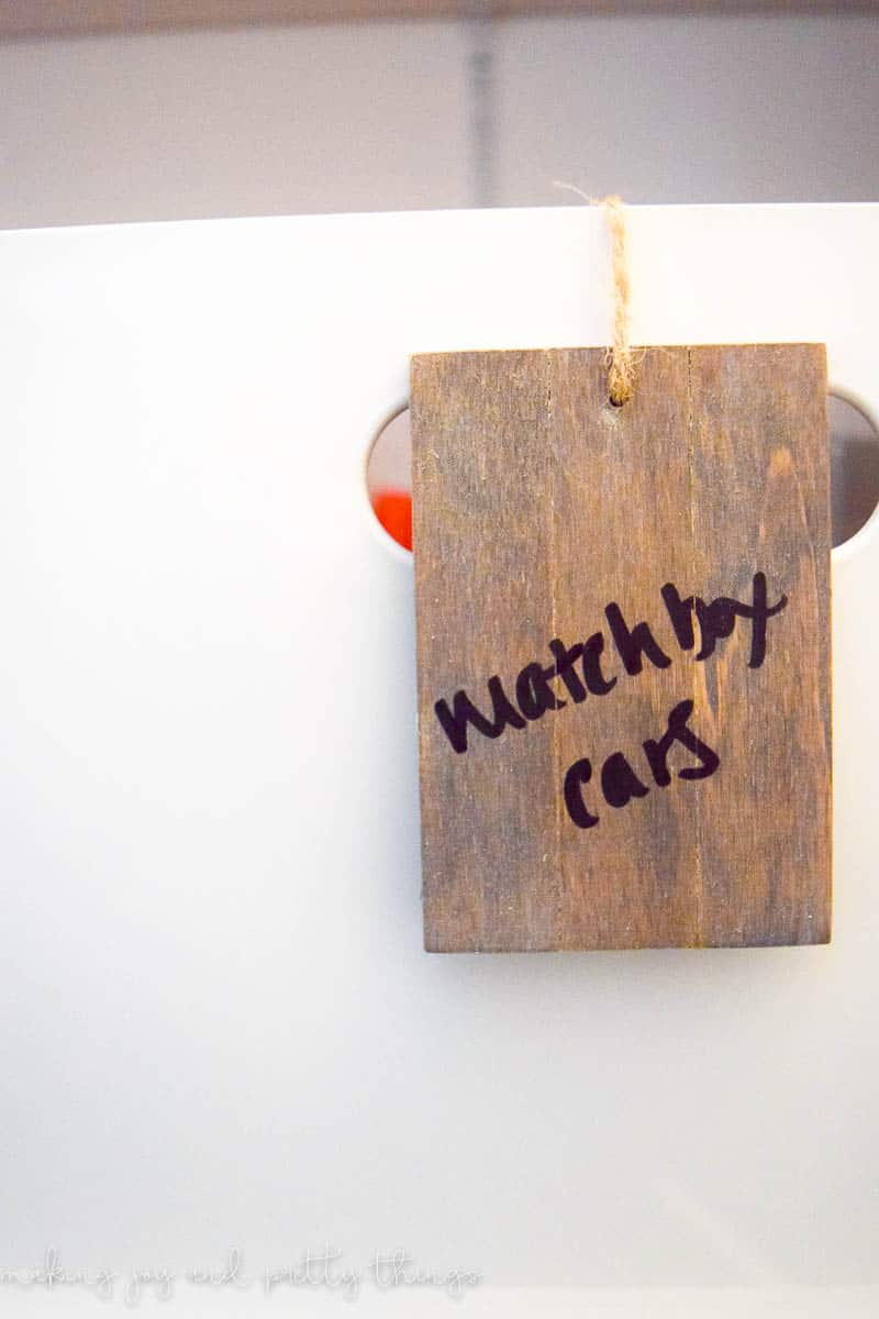 A small wood basket label hangs from a piece of twine. This basket label reads 