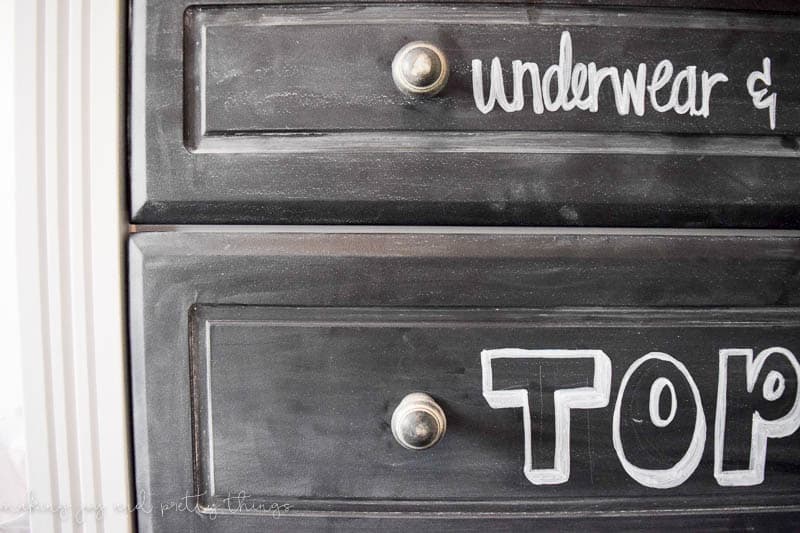 A close up look at a chalkboard painted dresser with silver knobs. 