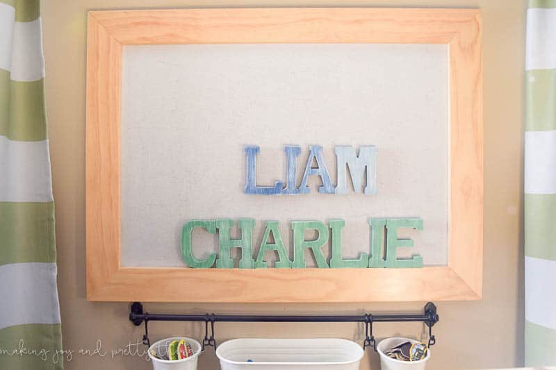 A photo of ombre distressed magnet letters for each little boy, with an IKEA kitchen storage system to hang fun buckets that are perfect for storing the rest of the magnets.