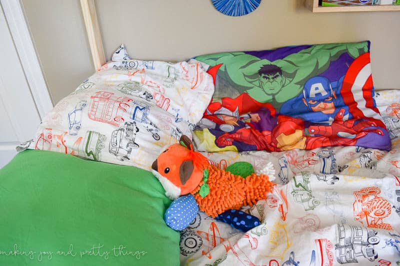 The bed is covered with 3 pillows and a stuffed animal.