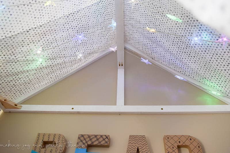 A photo of a DIY reading nook tent with bookshelves and star lights.