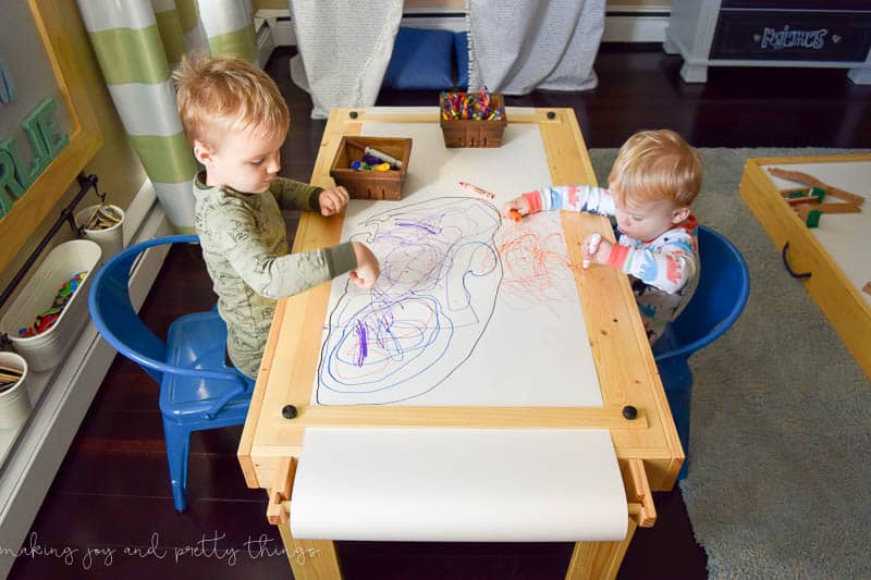 A photo of two children drawing on a table together.