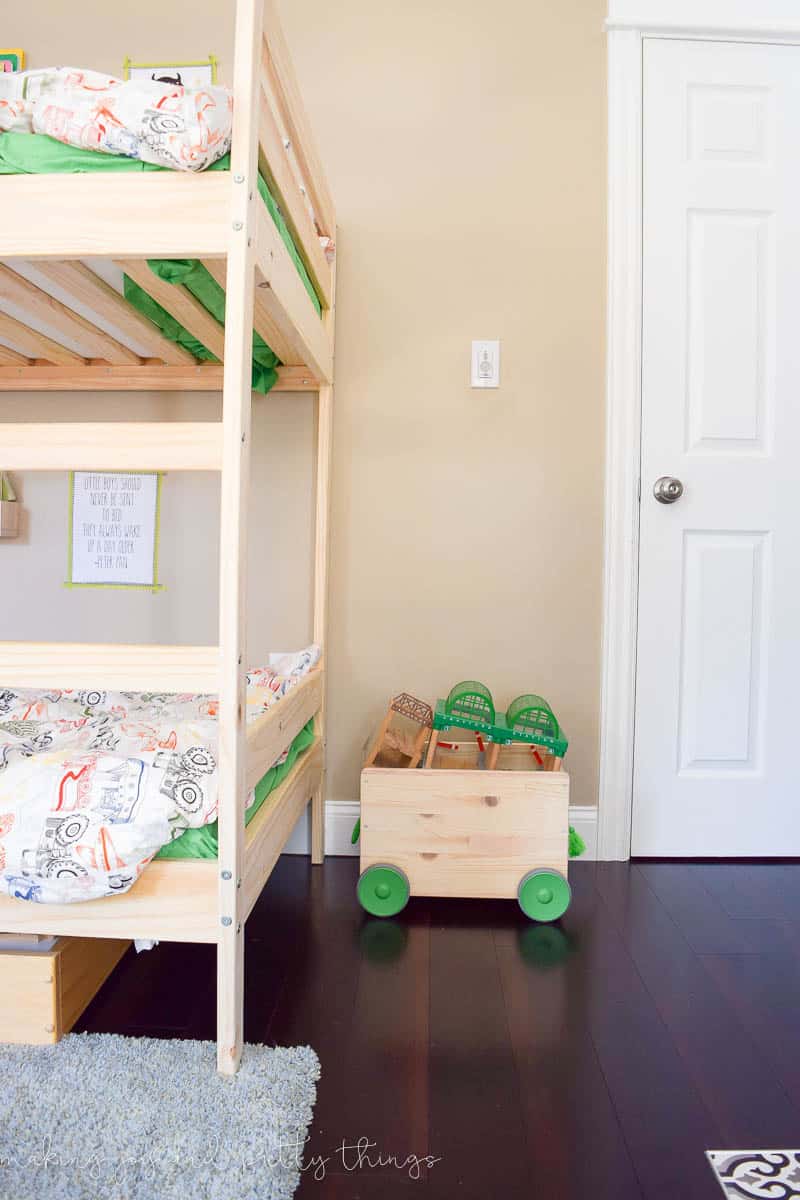 A photo of cutest rolling storage bin from IKEA to store the trains and tracks for the train table beside the bunk bed.