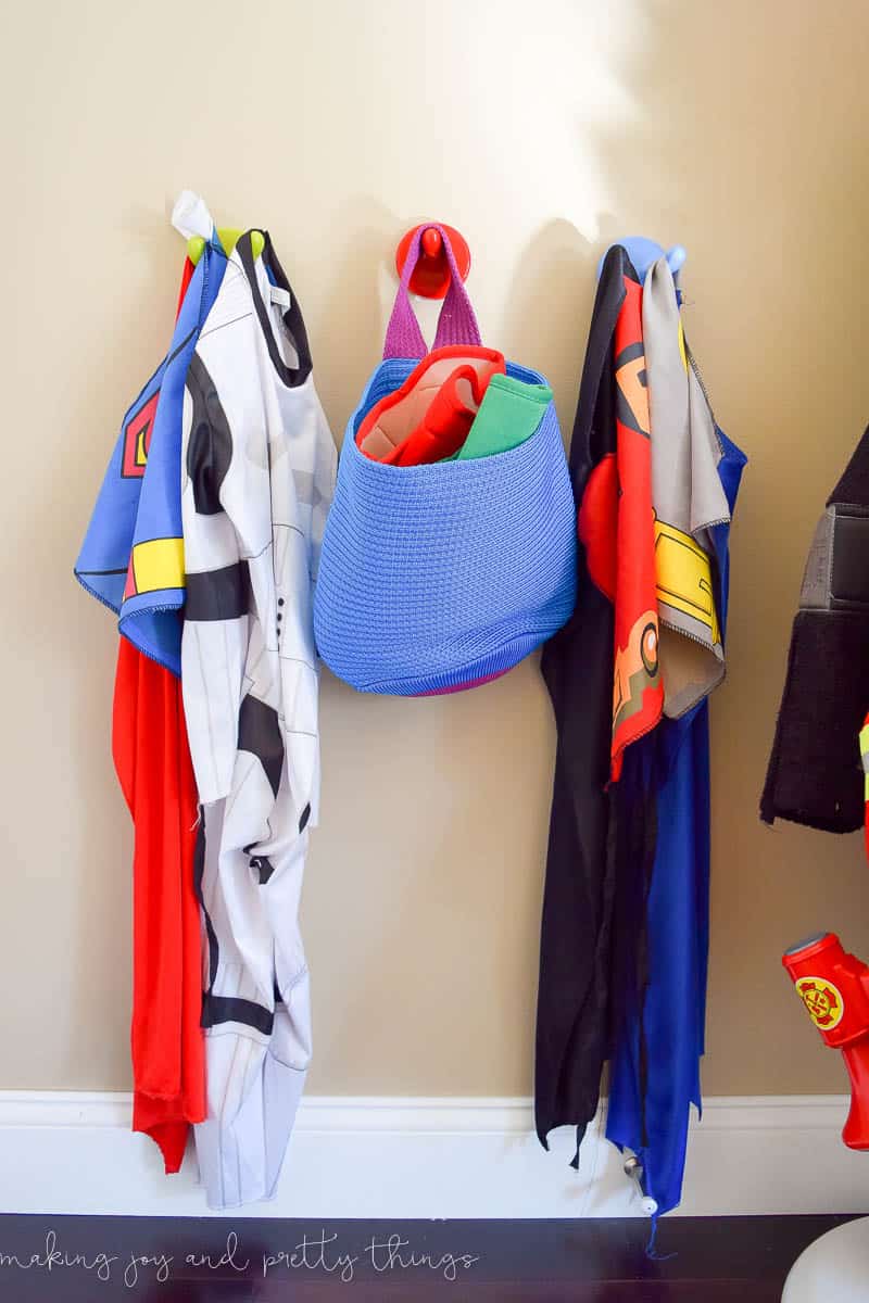 A photo of a boys' dress-up storage area, with hooks on the wall to hang costumes.