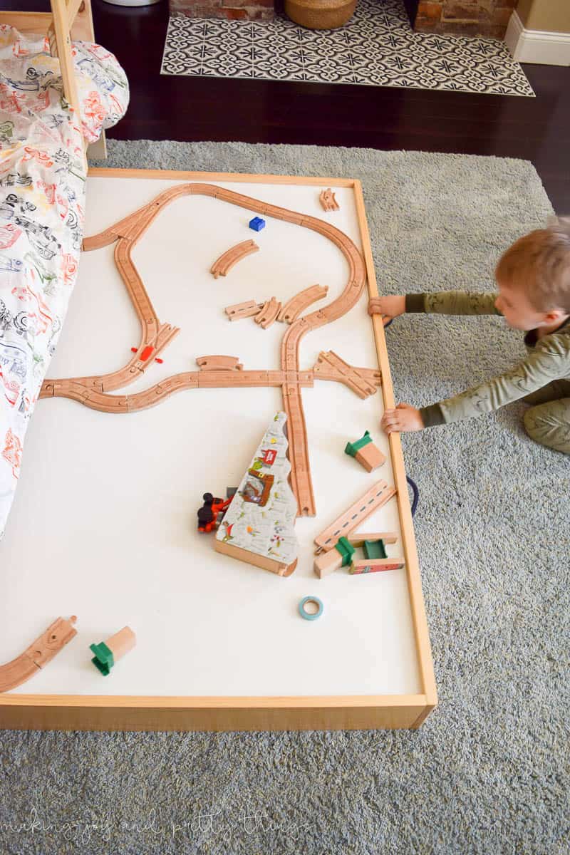 Under bed storage with a train table and a cute boy on the photo.