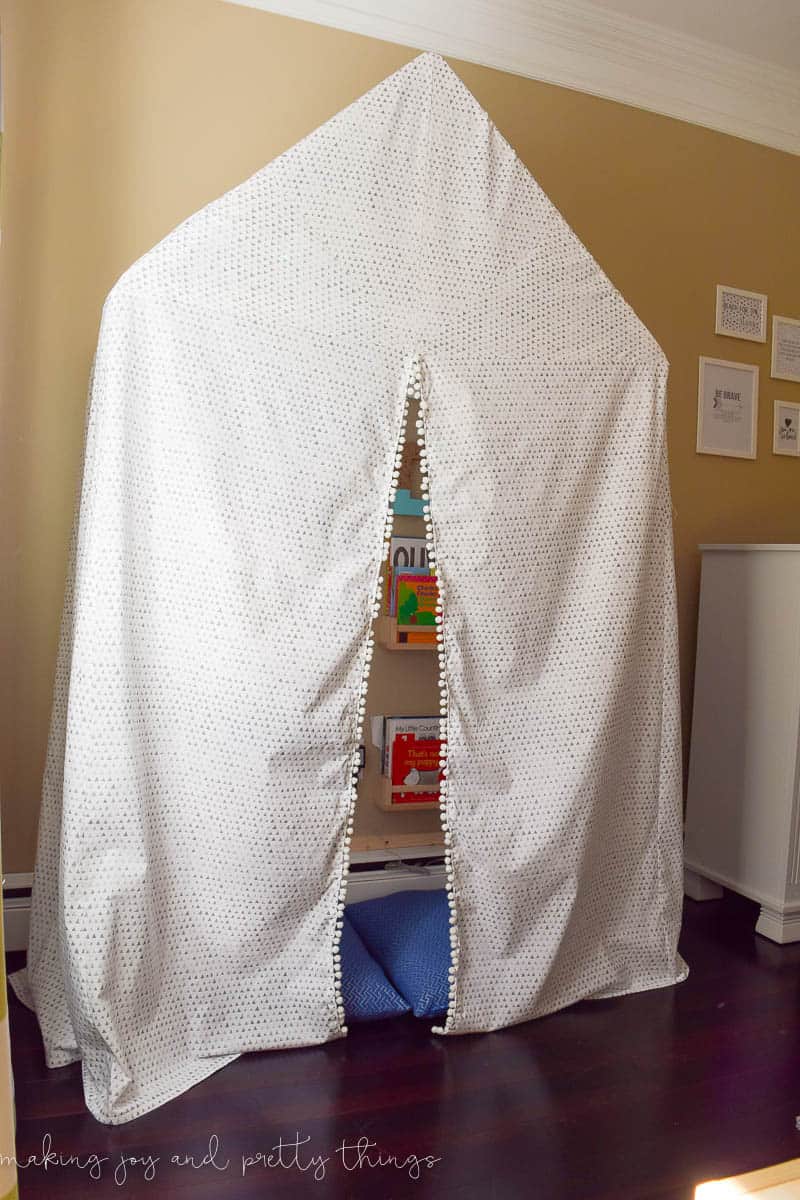 A photo of a DIY reading nook white tent with book storage.