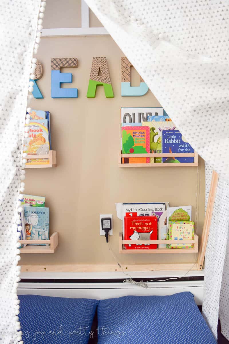 A photo of a DIY reading nook tent with bookshelves and two pillows.