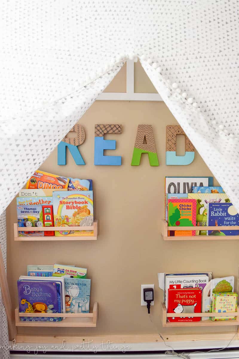 A close up photo of a DIY reading nook tent with bookshelves, showing the books and other items inside.