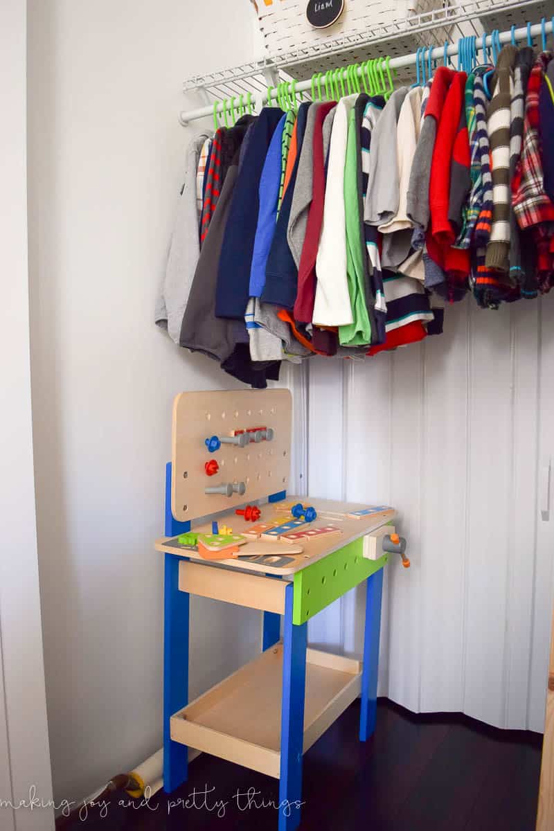 A photo of a hook that works well on the cabinet closet with clothes hung from it and a tool bench under it.