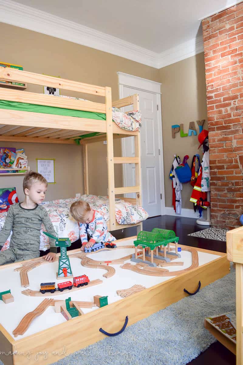 Under bed storage with a train table and two boys in the photo.