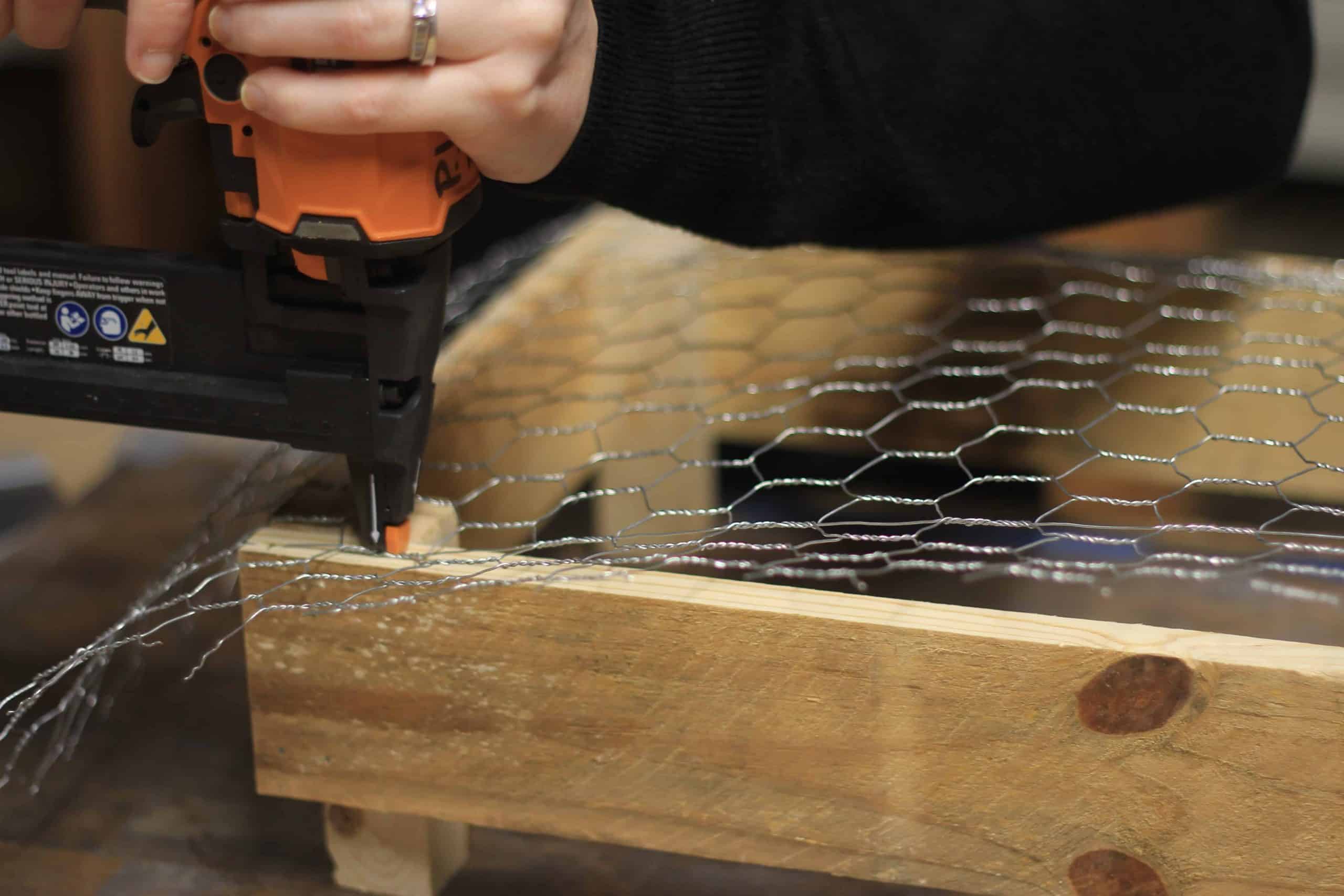 Adding chicken wire mesh to a DIY pallet crate to have a bottom to hold decorations and other kitchen utensils