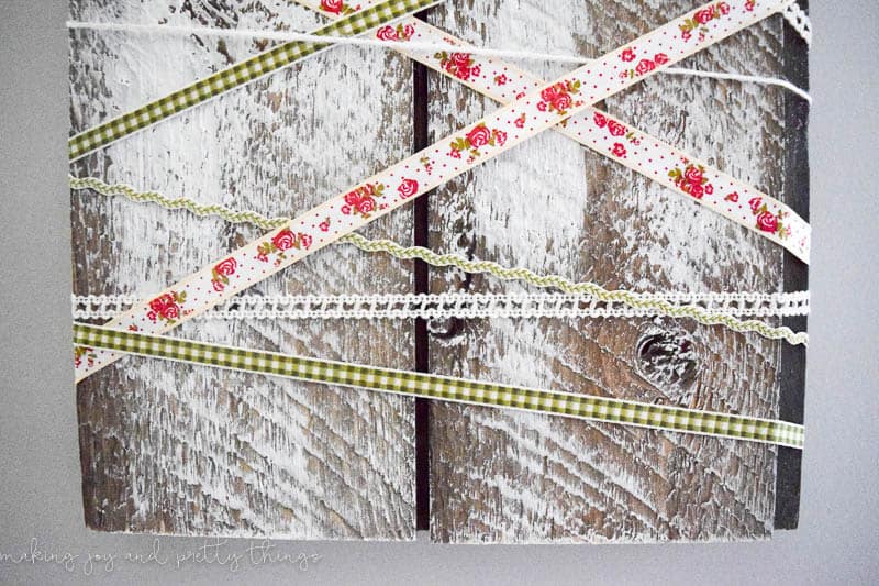 Close up of the ribbon wrapped shiplap painted in a linen grey to make a rustic farmhouse look for the holiday decor