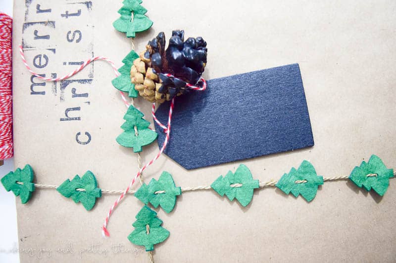 This rustic gift wrapping uses brown kraft paper, tree garland, pinecones, gift tags, and stamps.