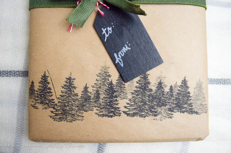 This rustic gift wrapping has a forest of pine tree stamps and a gift wrapped with ribbon and chalkboard gift tags.