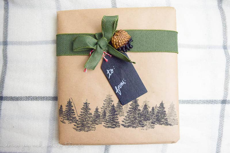 This rustic gift wrapping is my favorite of the bunch! A forest of pine tree stamps, and a brown krap paper-wrapped gift with a green burlap ribbon, paint-dipped pinecone, and a chalkboard gift tag.