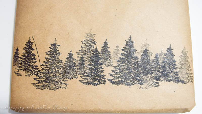 A forest of pine trees made with stamps on brown kraft paper. Use stamps like these to make DIY rustic gift wrapping for all your Christmas gifts.