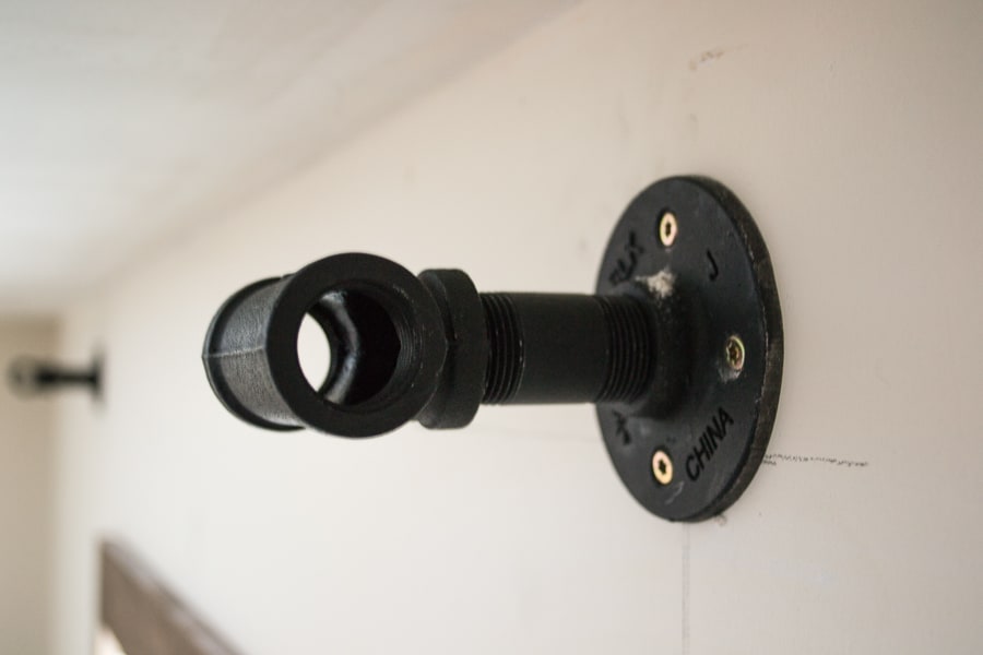 A matte black wall-mounted curtain rod holder attached to the wall with 4 screws.