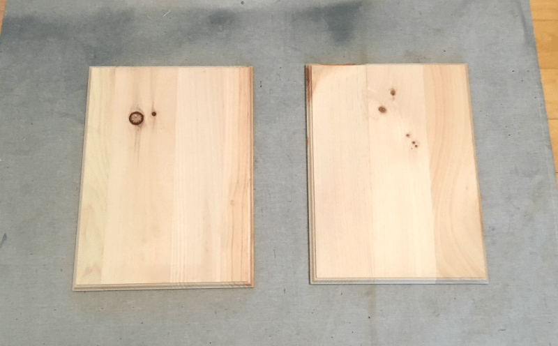 Two plain, natural pine wood boards sit on a gray work surface.