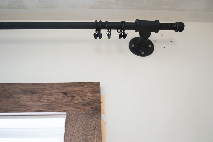 A look up at the pipe curtain rod attached to the wall, with curtain clips threaded onto the matte black pipe.