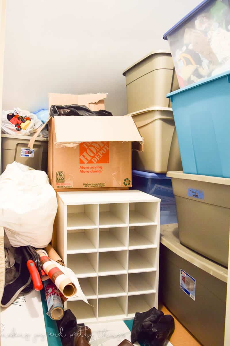 A small walk-in closet with sloped ceilings packed to the brim with storage totes, boxes, and clutter.