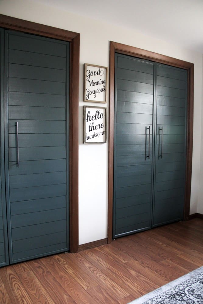 Two side-by-side closets with bi-fold shiplap closet doors painted a deep jade green color.