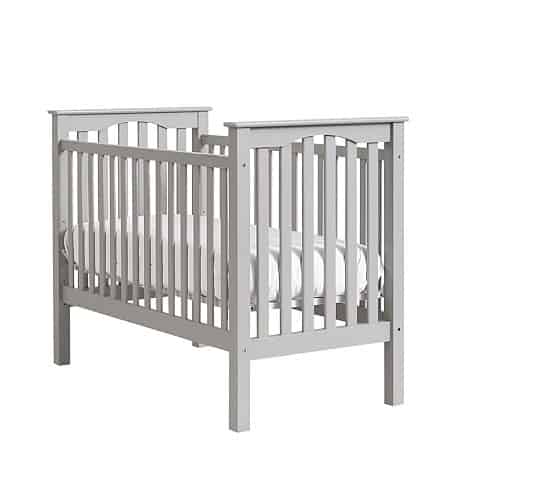 A plain white wooden crib with a crib mattress.