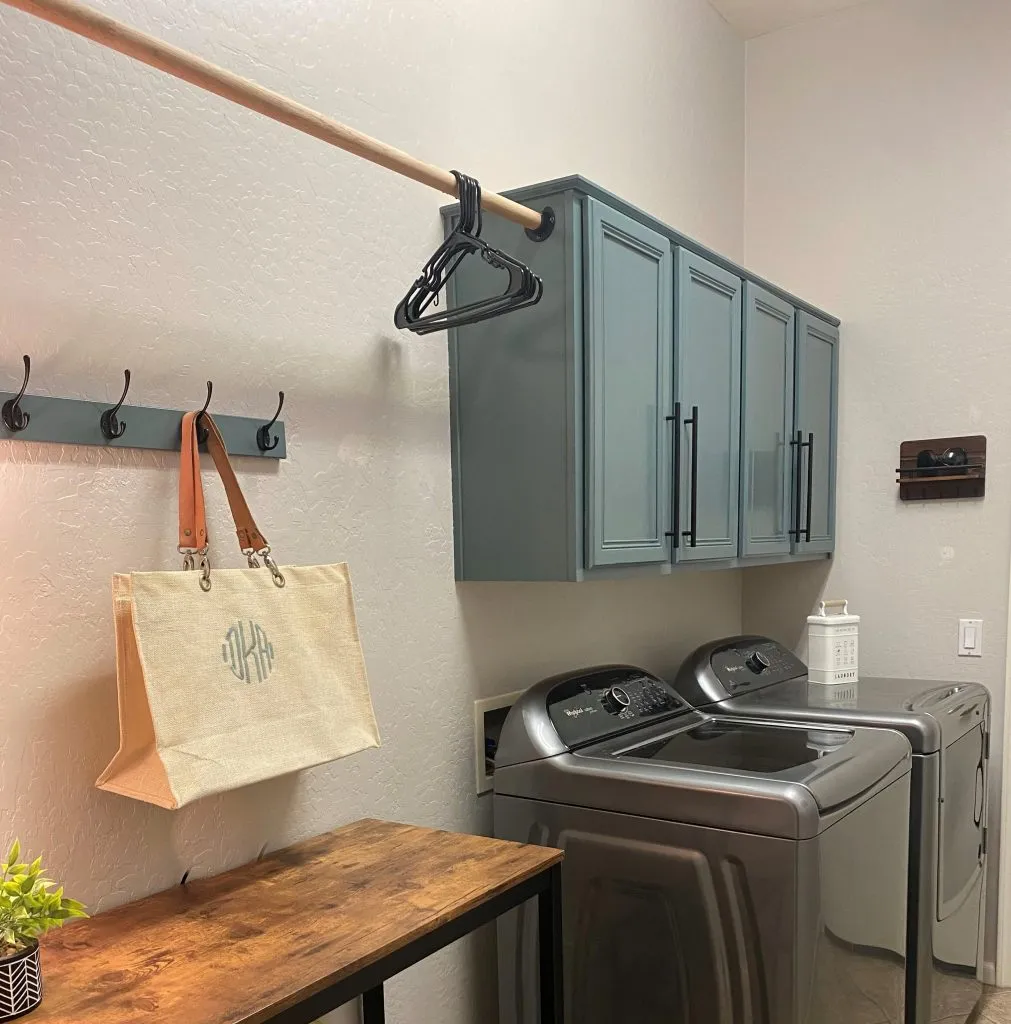 A pretty blue gray color, Duke Gray paint color from Magnolia Home by Joanna Gaines is used on this cabinet in this farmhouse style laundry room. 