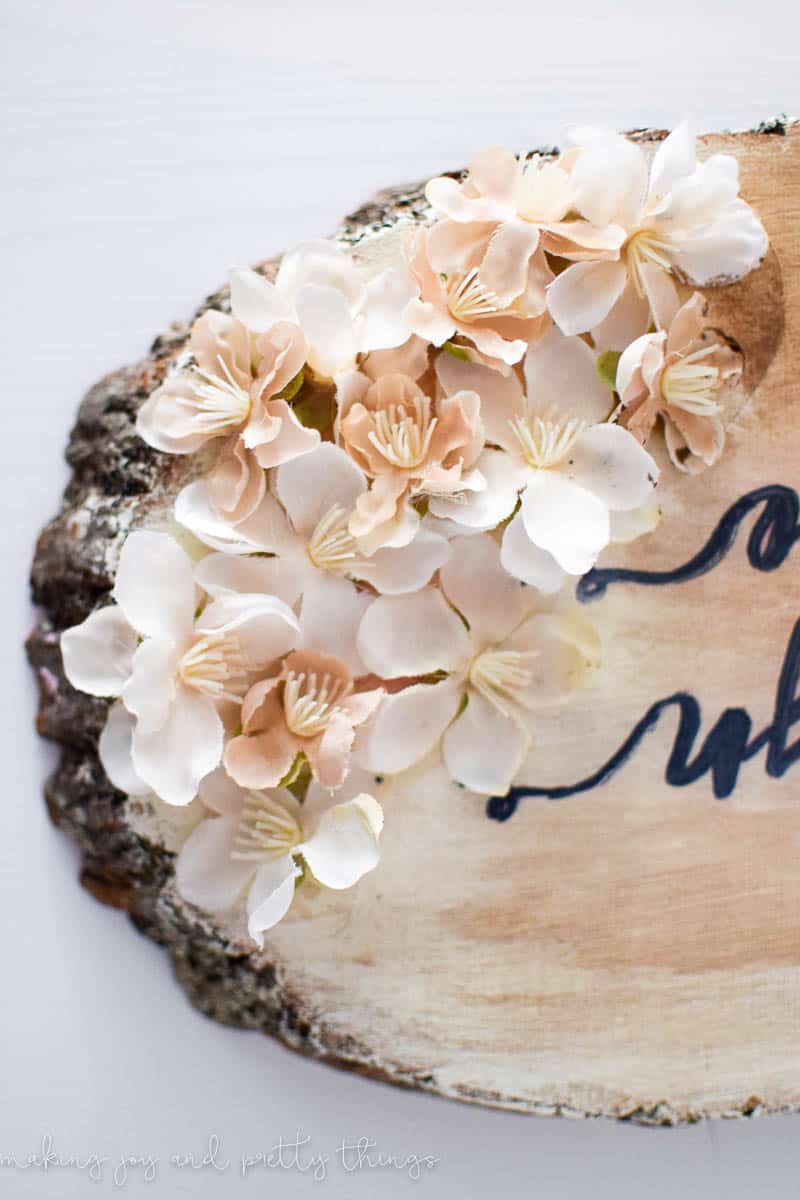 Adding flowers to the diy nursery name sign to add floral tones and balance the sign out with the cursive font