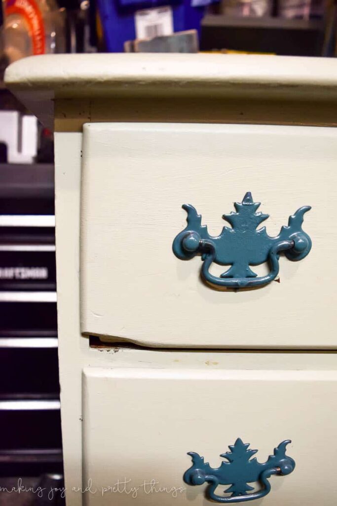 A closer look at the handles on an old thrifted dresser. The dresser is painted cream and the metal handles have been painted teal blue.