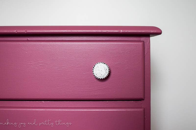A closer look at the new knob handles on the mauve pink dresser drawers. Each handle knob is white with bits of the original dark metal finish visible through white paint.