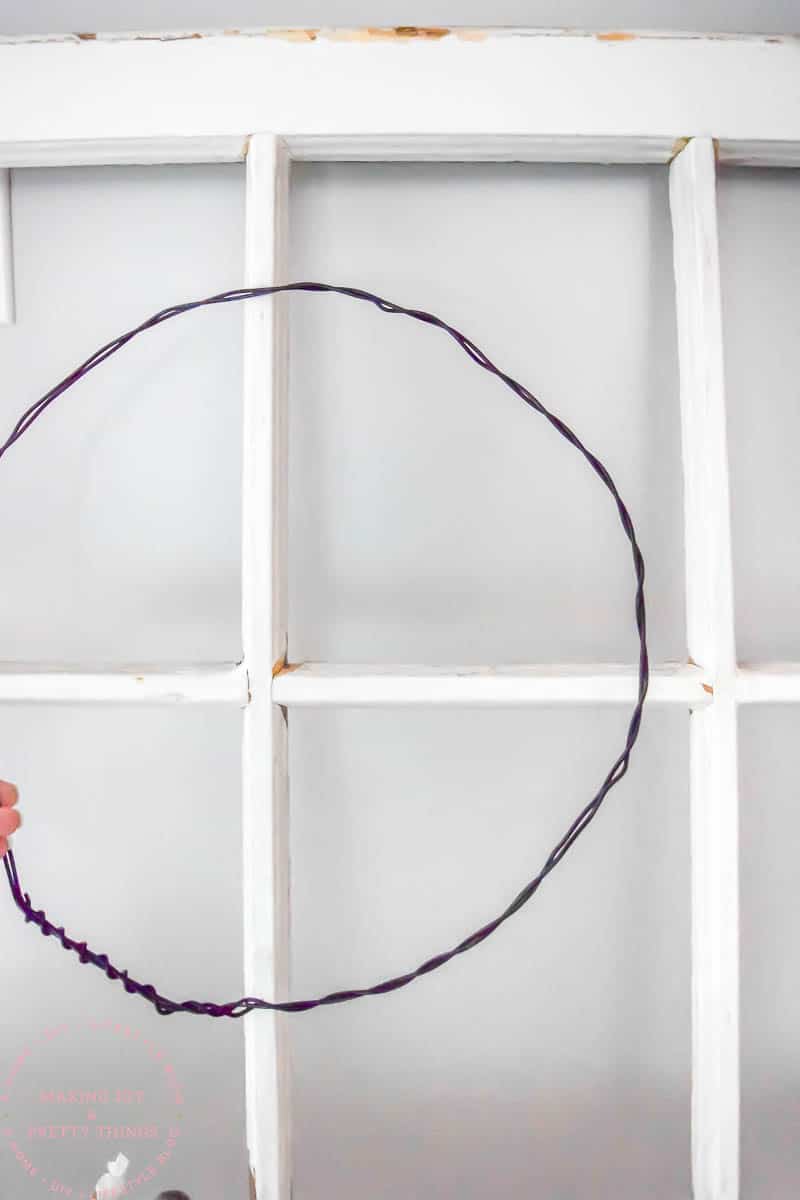 Wrapping decorative wire in a loop and holding up to a window for a DIY flower wreath 