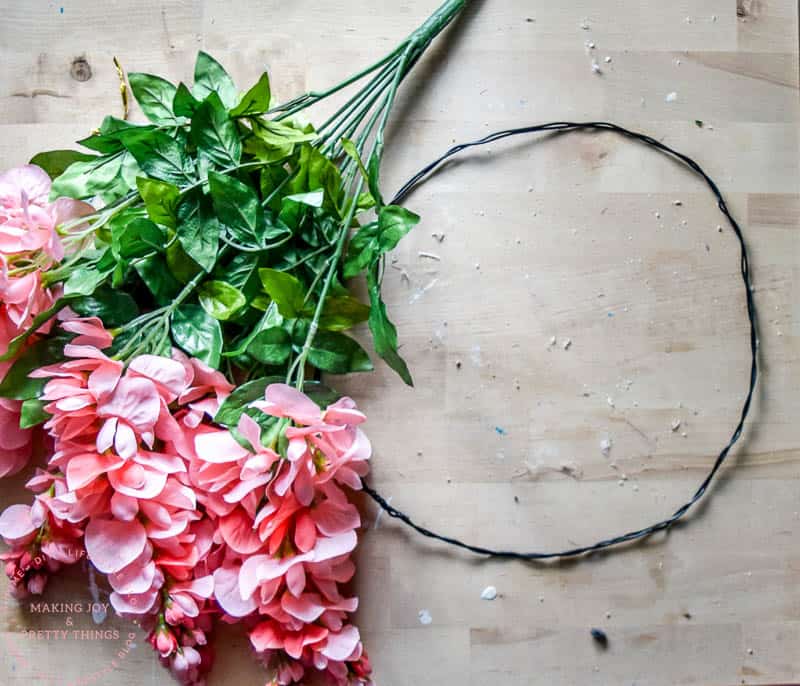 Supplies for a DIY Flower wreath using faux flowers and a decorative wire to attach in a loop