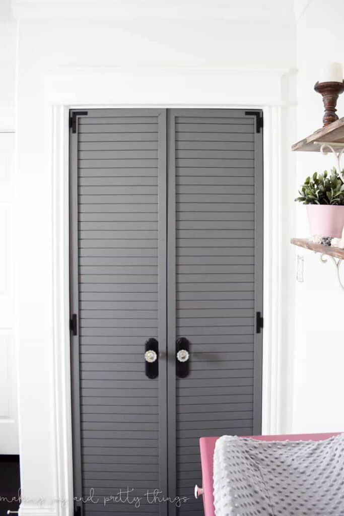 painted closet doors with black hardware and custom knobs in a farmhouse girls nursery with decor flair