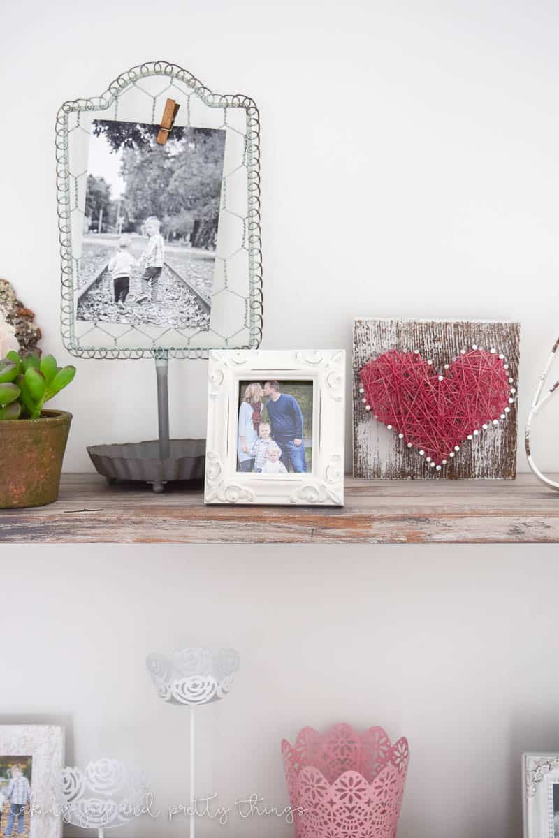 Family photos and decor displayed in a baby girl nursery on rustic farmhouse shelves making faux barnwood