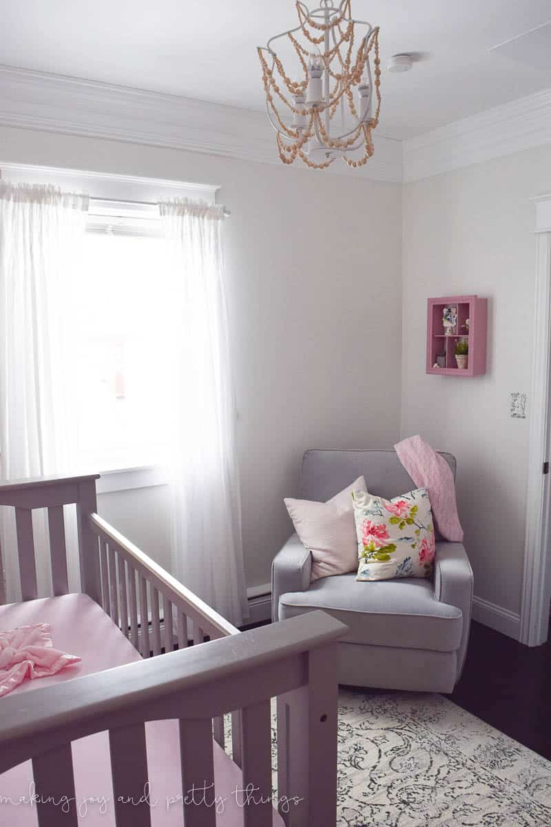 The sitting area of our girl's farmhouse style nursery, with a rocking chair and pillows.