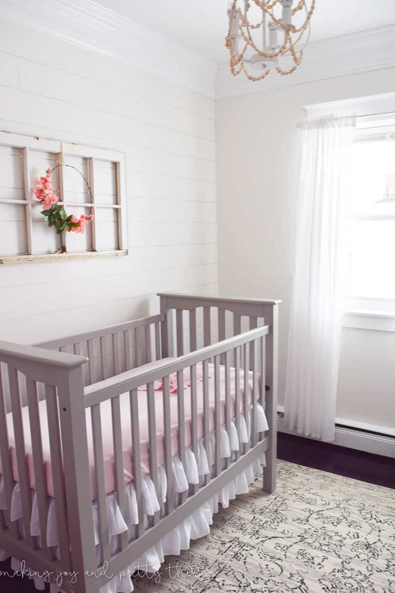 Baby girls nursery decorated in a farmhouse style with old window and updated curtain rods painted white