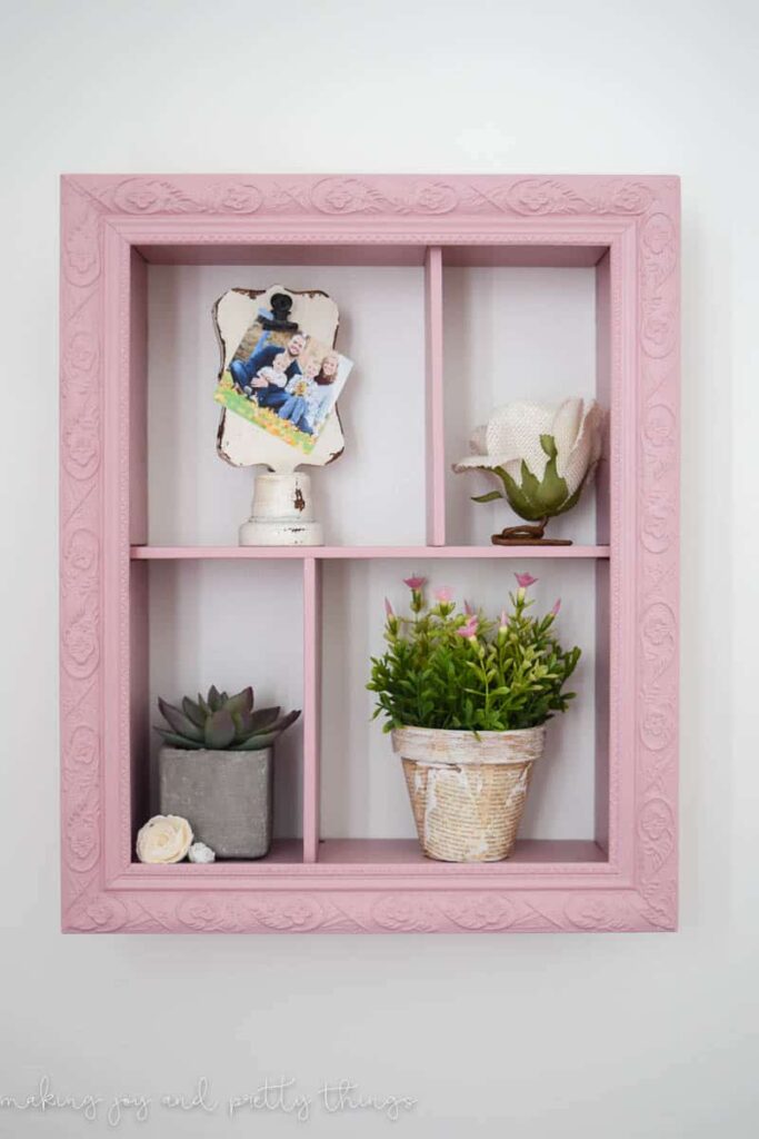 DIY shadow box painting in pink with potted plants clip frames and faux flowers to add a lot of farmhouse flair into a nursery