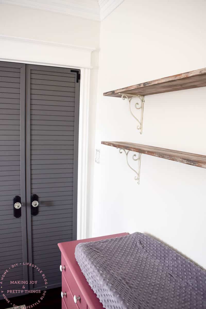 DIY rustic shelves with decorative brackets hung up on a nursery wall to give a farmhouse barnwood look