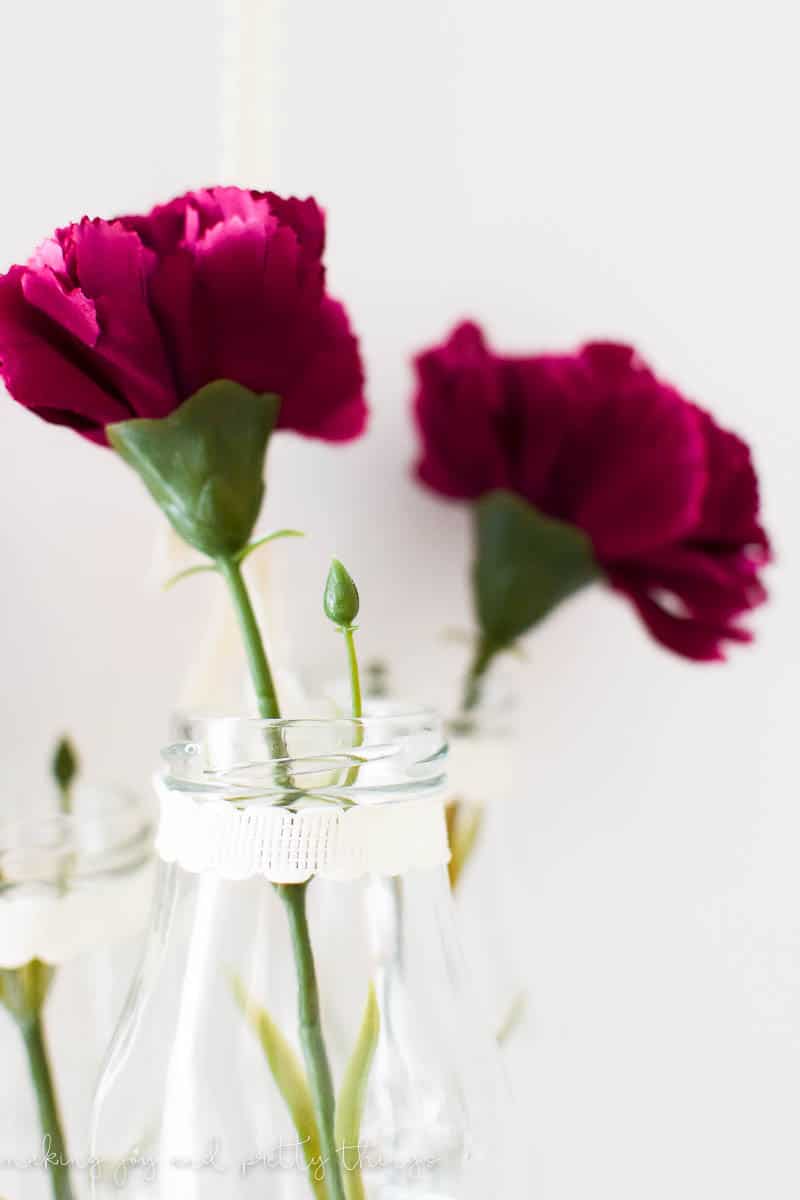 Close up of faux flowers in milke glass jars that have a mason look with farmhouse accents and ribbon 