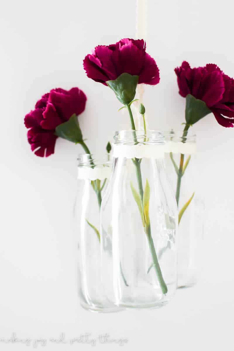 An easy farmhouse style DIY using milk jars and single stem flowers to make DIY hanging glass jars