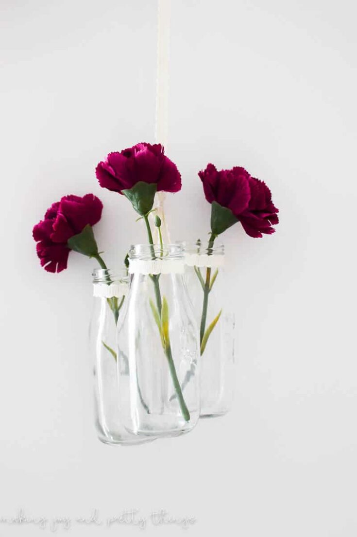An easy farmhouse style DIY using milk jars and single stem flowers to make DIY hanging glass jars