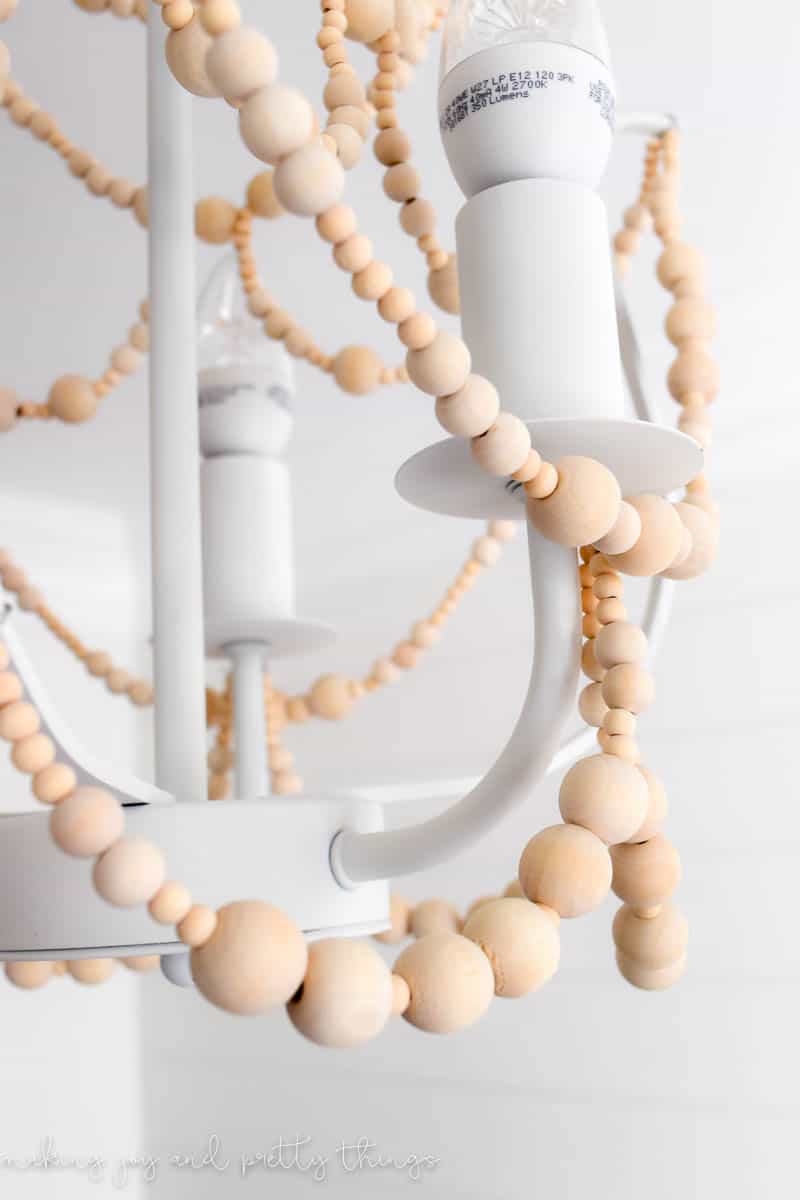 A close up look at strands of wood beads hanging on the IKEA chandelier.