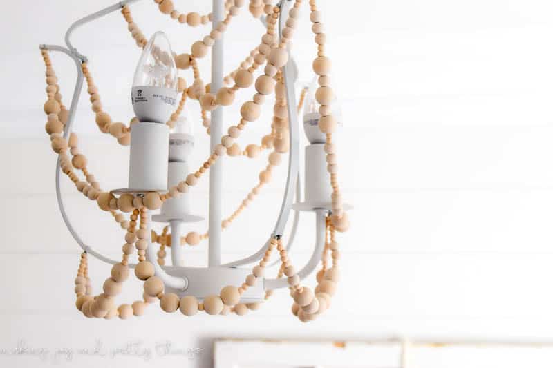 Learn how to make this easy diy wood bead chandelier, with strands of wood beads hanging from an IKEA chandelier frame.