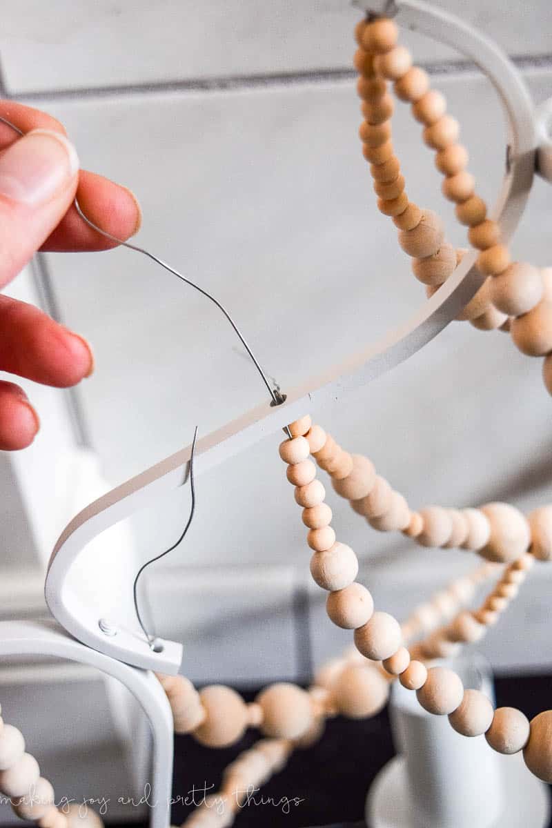 A close up look at how to attach the strands of wood beads to the body of the chandelier.