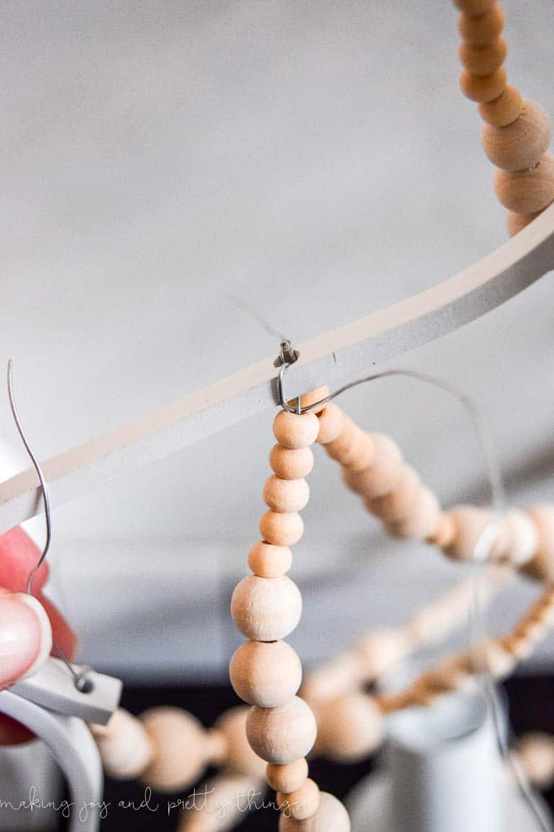 A close up look at how to secure the strands of wood beads to the chandelier body.