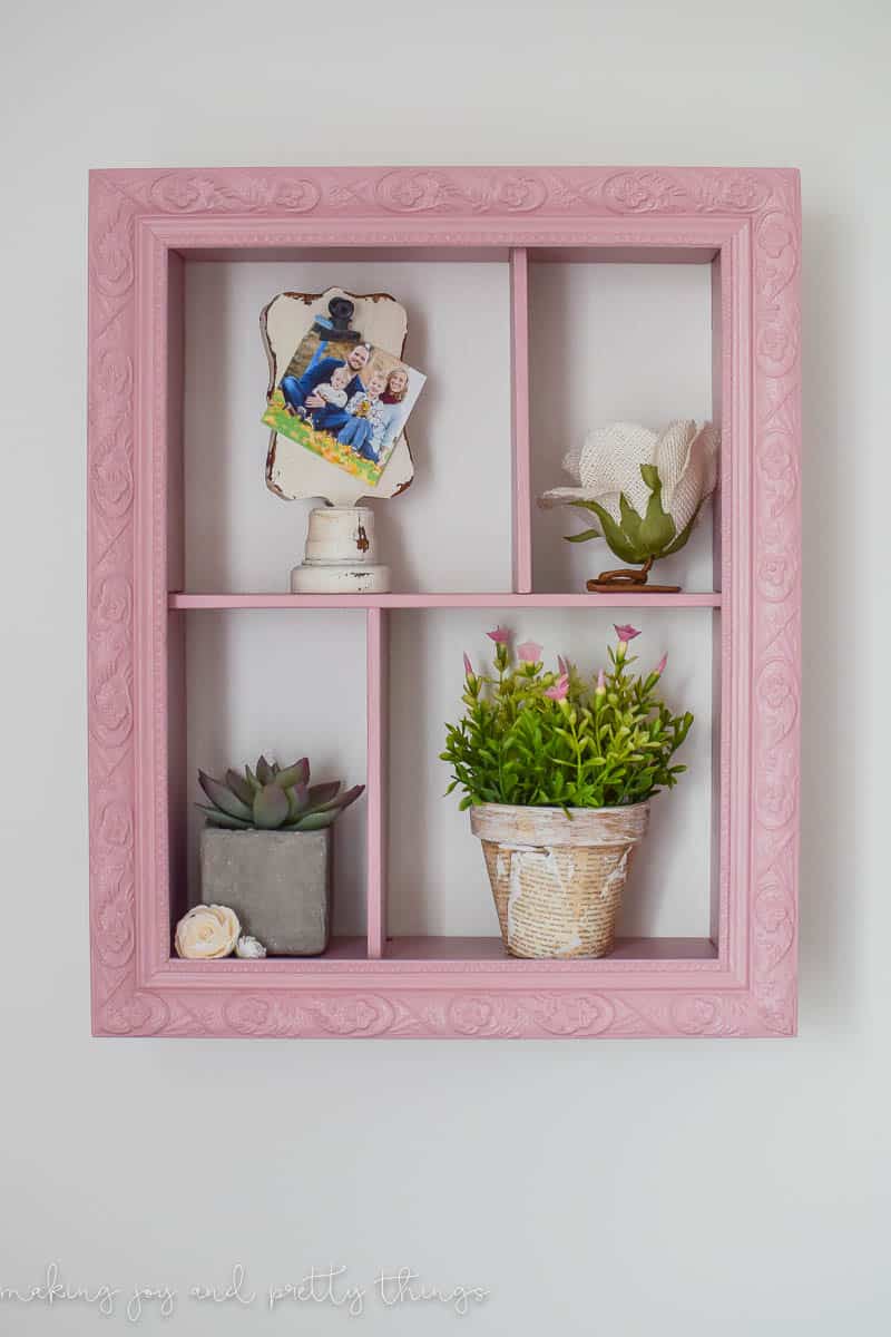 DIY shadow box handing on the wall with shelves using a picture frame for decor