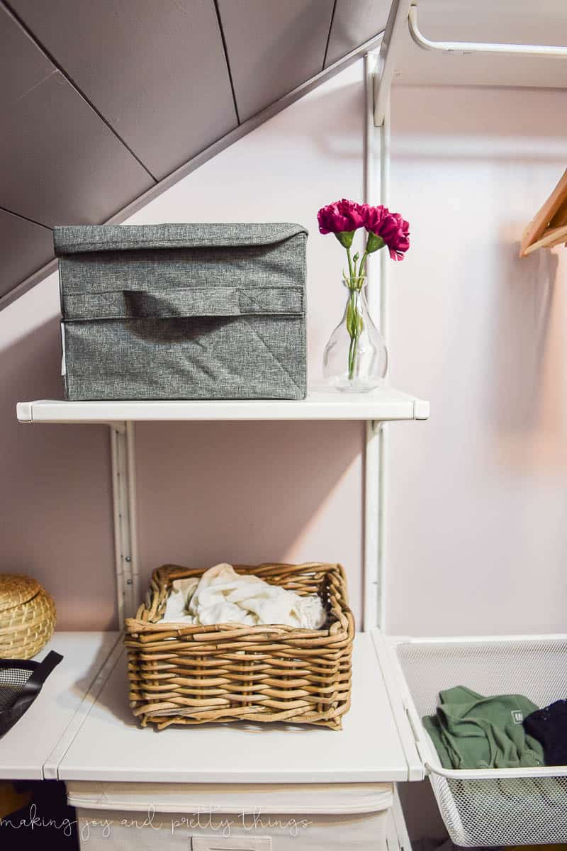 A closer look at some of the wall-mounted shelving included in the IKEA algot closet system. Shelves are installed on wall-mounted tracks and hold storage bins, baskets, and simple farmhouse decor.