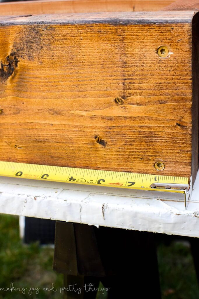 Using a tape measure and showing screws that are holding together a DIY vertical herb garden frame