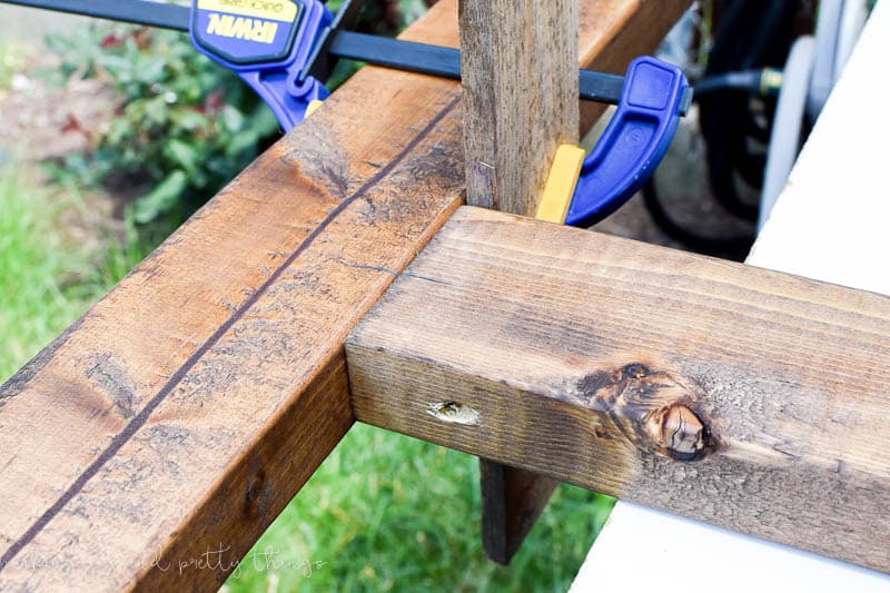Use clamps and scrap wood when screwing in a center beam onto a DIY vertical herb garden and planter