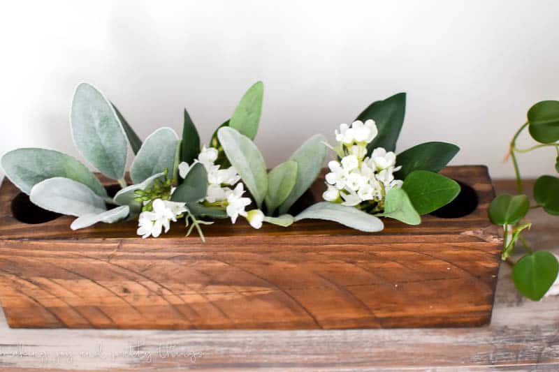 Farmhouse style sugar mold sitting on floating shelf holding faux flowers